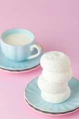 Pastel pink vertical banner with white zephyr on blue plate and cup of milk.