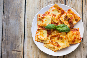 Plate of sweet ravioli  with olive sauce on the wooden table/white background, top view