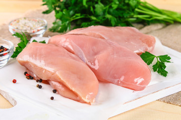 raw chicken fillets on wooden cutting board.