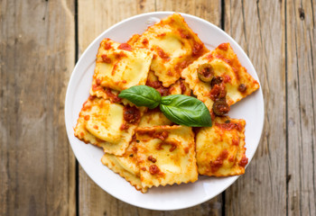 Plate of sweet ravioli  with olive sauce on the wooden table, top view