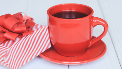 gift box and red Cup on a light wooden background