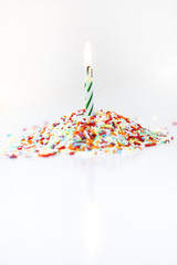 Burning white and green striped spiral birthday candle for dopping cakes, cupcakes or muffins as...