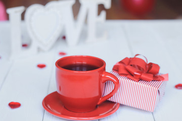 Cup of coffee and gift on blurred background.