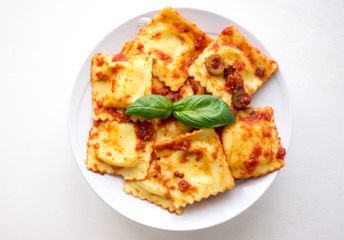 Plate of sweet ravioli with olive sauce on white background, top view