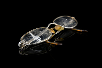 Old broken eyeglasses on black background, reflection on surface, move for create place for text. Fashion, style and healthcare
