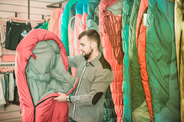 Smiling guy deciding on new sleeping bag