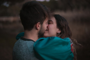 A cute spanish couple having a nice afternoon hugging and kissing each other in a park in front of a lake in Seville, Spain.