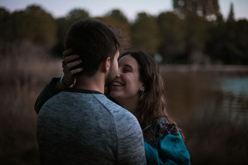 A cute spanish couple having a nice afternoon hugging and kissing each other in a park in front of a lake in Seville, Spain.
