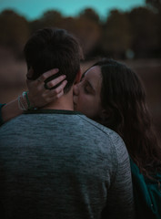A cute spanish couple having a nice afternoon hugging and kissing each other in a park in front of a lake in Seville, Spain.