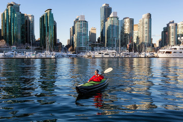 Man on an inflatable kayak is kayaking in Coal Harbour during a sunny morning. Taken in Downtown Vancouver, British Columbia, Canada. - obrazy, fototapety, plakaty