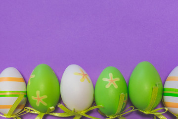 Fototapeta na wymiar Top view of colorful green, white and orange Easter eggs decoration on purple background with copy space, Happy Easter Background