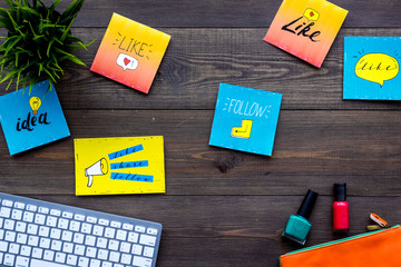 Beauty blogging concept. Work desk with keyboard, cosmetics and social media icons on dark wooden desk top view