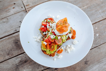 Healthy Breakfast with Wholemeal Bread Toast and Poached Egg with tomatoes, avokado, cheese and Beckon on the wooden background.