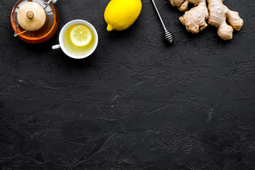 Tea for cure colds. Cup, teapot, ginger root and lemon on black background top view copy space