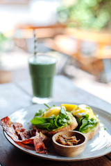 Healthy Breakfast with Wholemeal Bread Toast and Poached Egg with salad, avokado and Beckon.Green smoothie on the background. Vertical photo