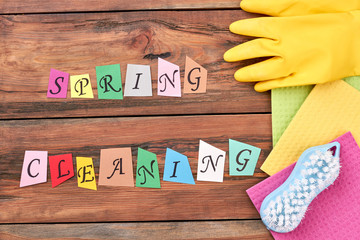 Accessories for cleaning on wooden background. Cut out colorful letters spring cleaning on wooden floor. House preparation for spring.