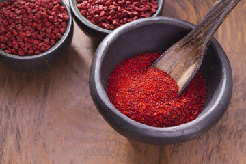 achiote in bowl on wooden background, achiote paste