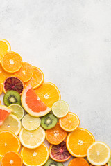 Assortment of citrus fruits and kiwis on white table background, top view, copy space, vertical, selective focus