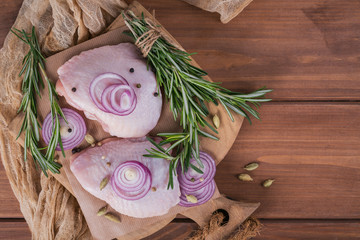 Raw chicken thighs with rosemary, red onion and peppercorns