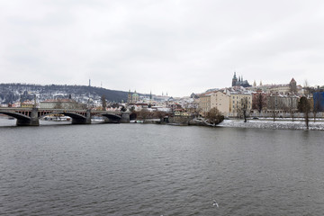 Obraz premium Snowy Prague Lesser Town with gothic Castle above River Vltava, Czech republic