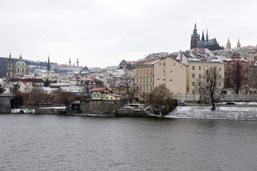 Snowy Prague Lesser Town with gothic Castle above River Vltava, Czech republic