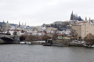 Naklejka premium Snowy Prague Lesser Town with gothic Castle above River Vltava, Czech republic