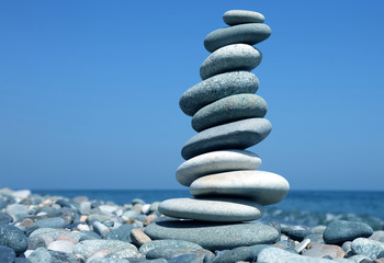 balance a pyramid of smooth stones on the background of the sea