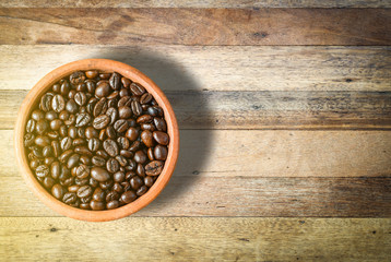 Obraz na płótnie Canvas top view of roast Coffee Beans in a cup on wooden table background