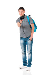 Naklejka premium Teen student boy with headphones and backpack. Guy pointing at camera choosing you, isolated on white background. Portrait of young man pointing forefinger to front, gesture and people concept.