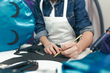 Close-up man working in the craft workshop. Young designer drawing on rubber eva. Customizing a...