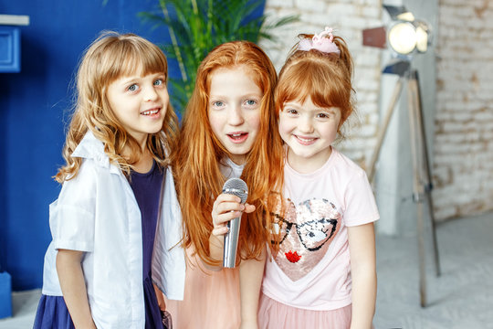 Three kids sing a song in a microphone. Group. The concept is childhood, lifestyle, music, singing, friendship.