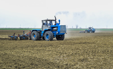 Lush and loosen the soil on the field before sowing. The tractor plows a field with a plow