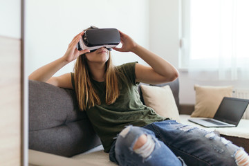 Beautiful young woman enjoying virtual reality at her home.