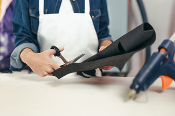 Young craftsman in the craft workshop trimming with scissors. Craftsman hipster working in his workshop.