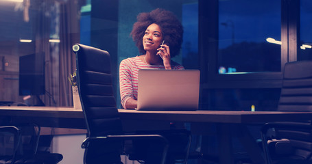black businesswoman using a laptop in night startup office