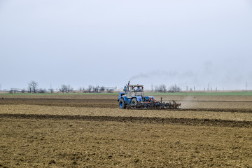 Lush and loosen the soil on the field before sowing. The tractor plows a field with a plow