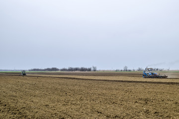 Lush and loosen the soil on the field before sowing. The tractor plows a field with a plow