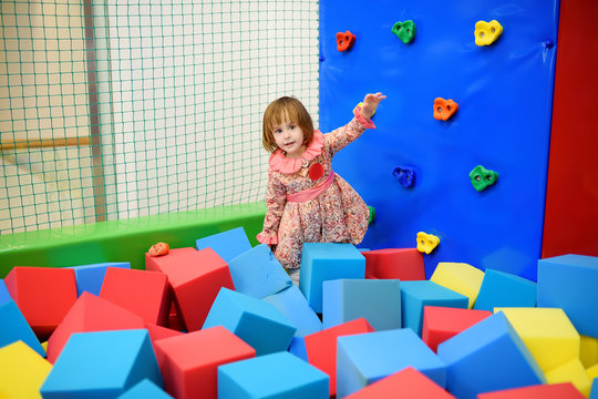 Cute toddler girl having fun in indoor leisure center for kids