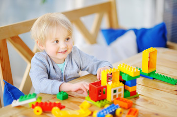 Little boy playing with colorful plastic blocks at kindergarten or at home