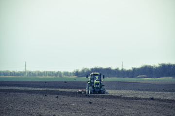 Lush and loosen the soil on the field before sowing. The tractor plows a field with a plow