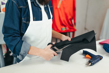 Young craftsman in the craft workshop trimming with scissors. Craftsman hipster working in his workshop.
