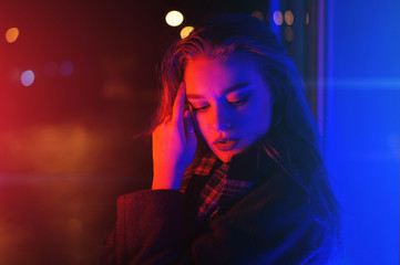 Sexy young woman posing over night city dramatic neon background