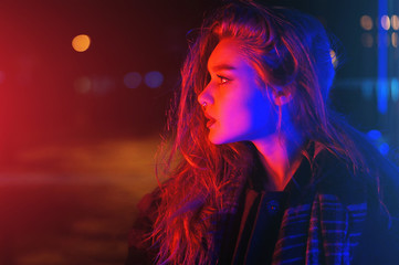 Sexy young woman posing over night city dramatic neon background