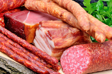 Delicious smoked sausages with bacon and salami on a wood board