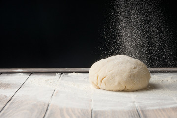 The dough lies on the working surface. With a black background. The power concept.