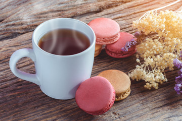 Different types color of macaroons with Cup of hot tea on Old grunge wooden background