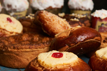 Homemade Russian Easter baked goods, kulichi, patties with cottage cheese, karavai and loaf cake with nuts on festive table background