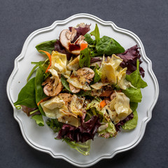 Top view of healthy organic salad on white plate on dark background