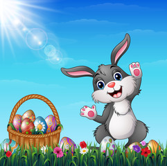 Easter bunny with Easter basket full of decorated Easter eggs in a grass field