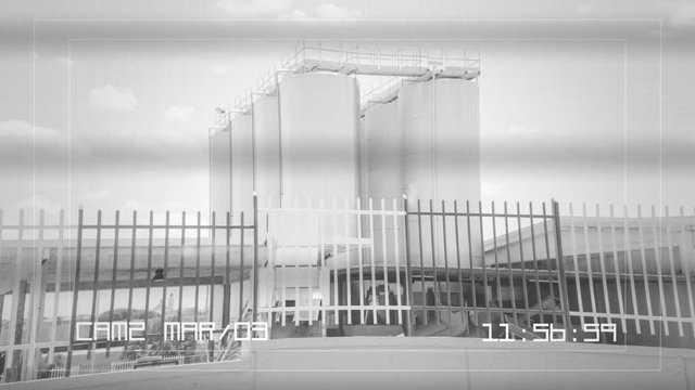 A CCTV security camera recording: industrial silos (huge containers made of stainless steel). Close-up shot.
